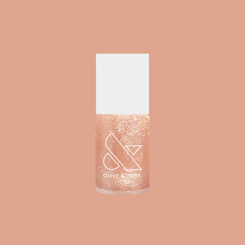 Olive and June Cookie Swap nail polish bottle with shimmery beige champagne gel polish on peach background