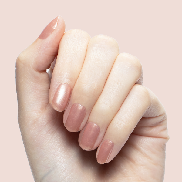 Hand with medium-length nails painted in shimmering Cookie Swap polish against soft pink background
