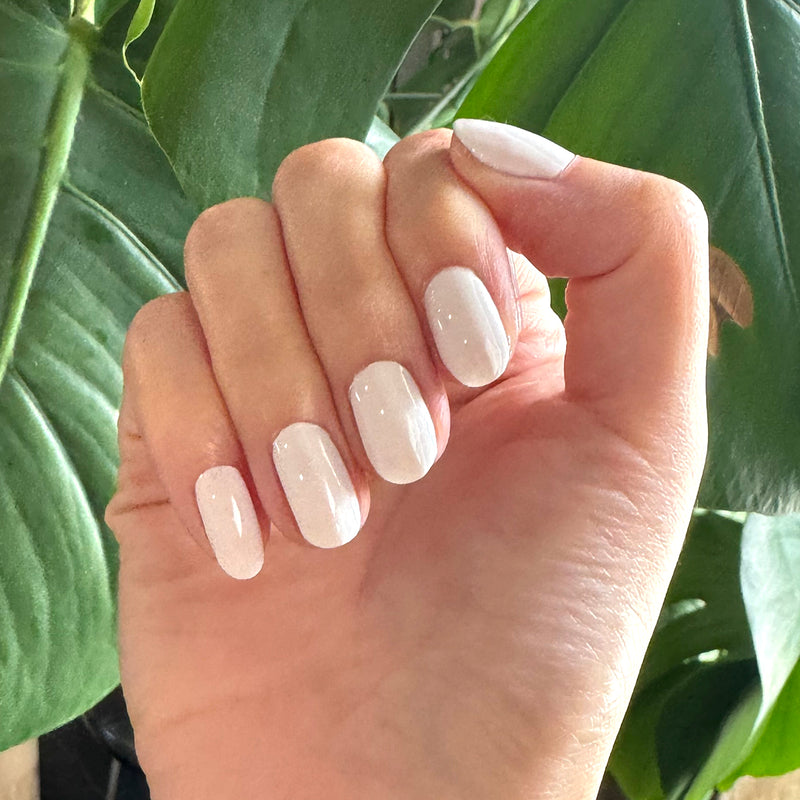 Hand with short oval nails polished in crisp white shade from Sheer & Neutral Gel Polish Set for at home manicure