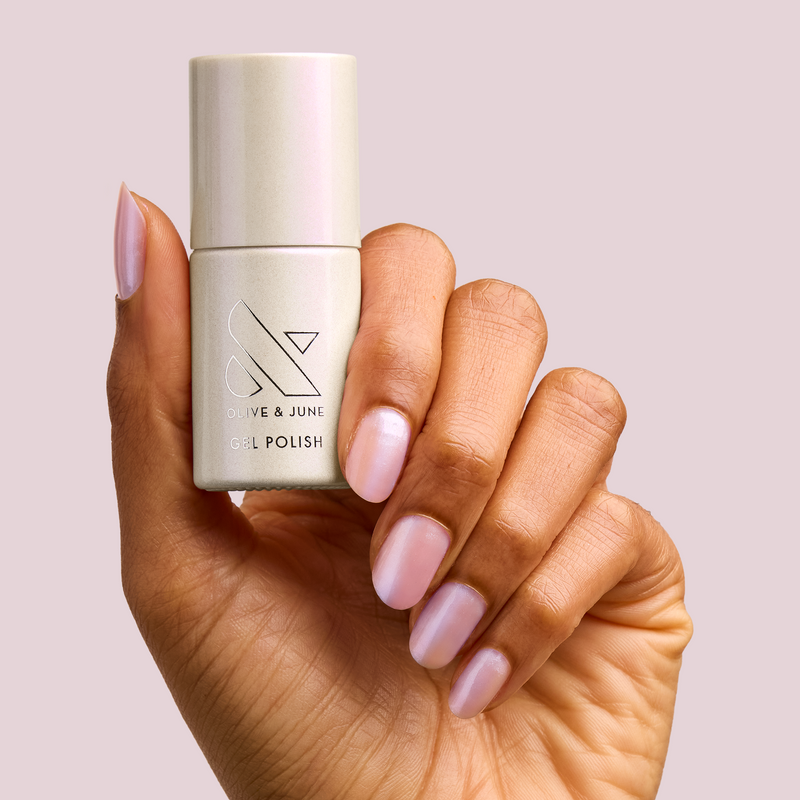Hand holding BAROQUE Gel bottle with nails painted in pearly white iridescent gel polish for manicure and at-home use