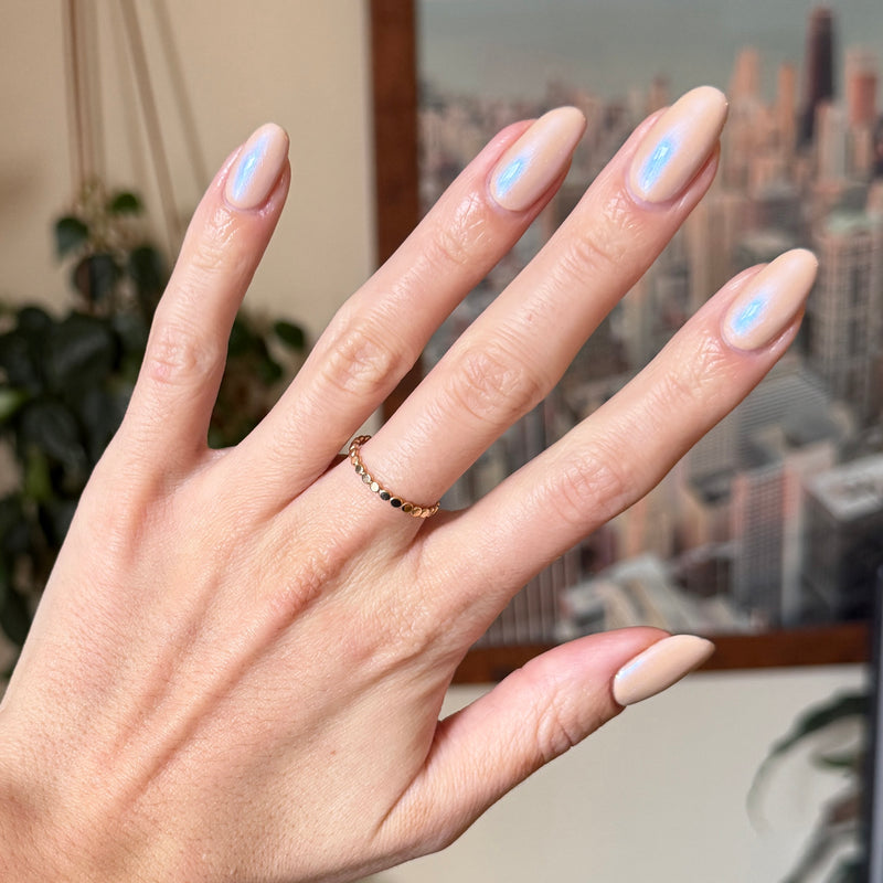 Country Chrome manicure on almond-shaped nails with shiny neutral polish shown against indoor city backdrop