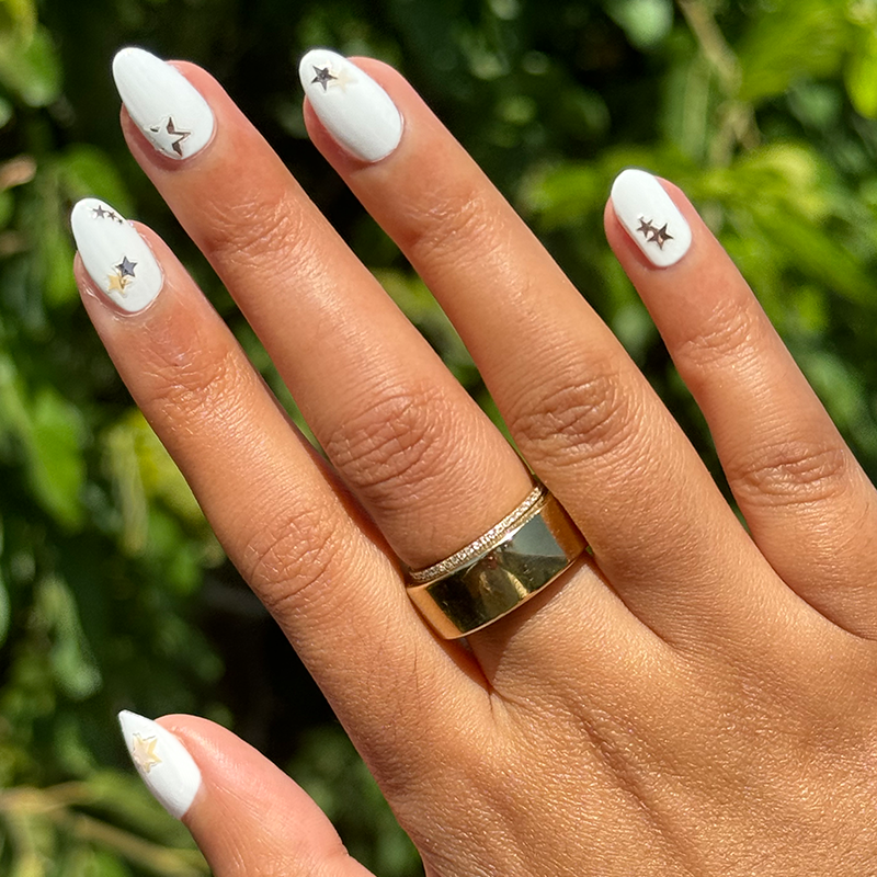 Be a Star Set showing pearly white manicure with metallic star nail stickers on natural hand in outdoor light