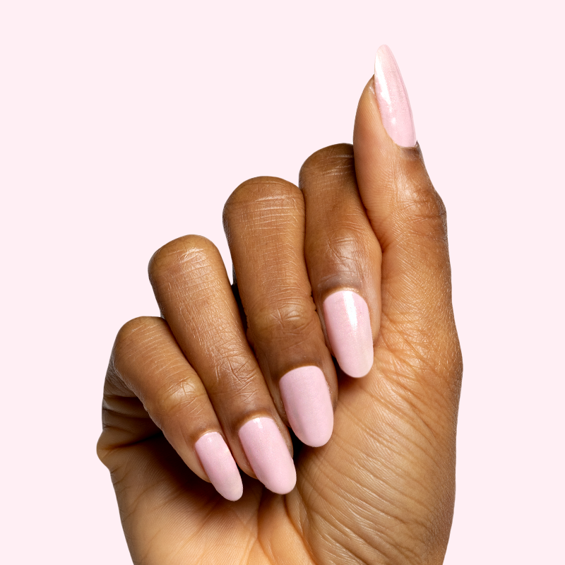 Hand with soft pink manicure showcasing nails coated with Speed Gloss Top Coat on a pale pink background