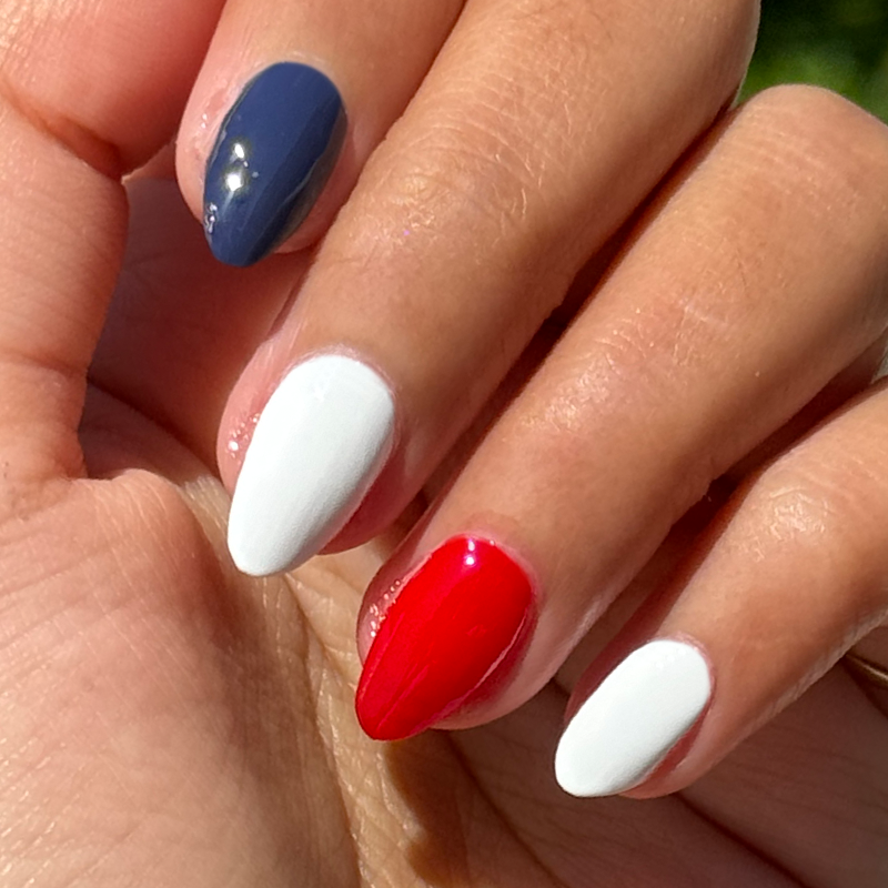 Festive Flag Set featuring shiny red, white, and indigo blue manicure on short almond-shaped nails in natural light