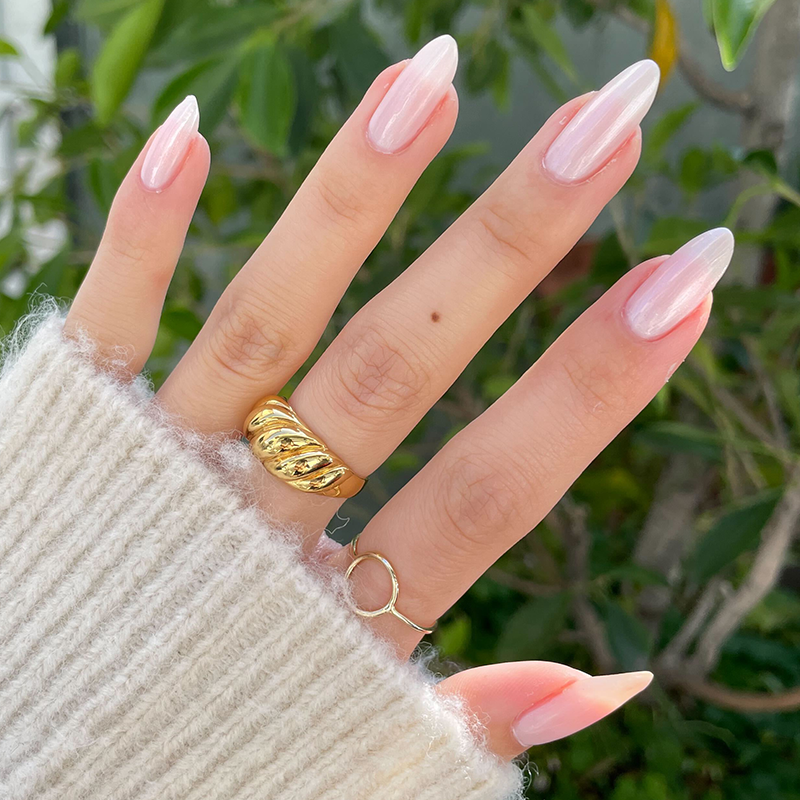 Pearl Polish Set featuring neutral pink nails with a pearlescent shimmer on long, almond-shaped nails with gold rings