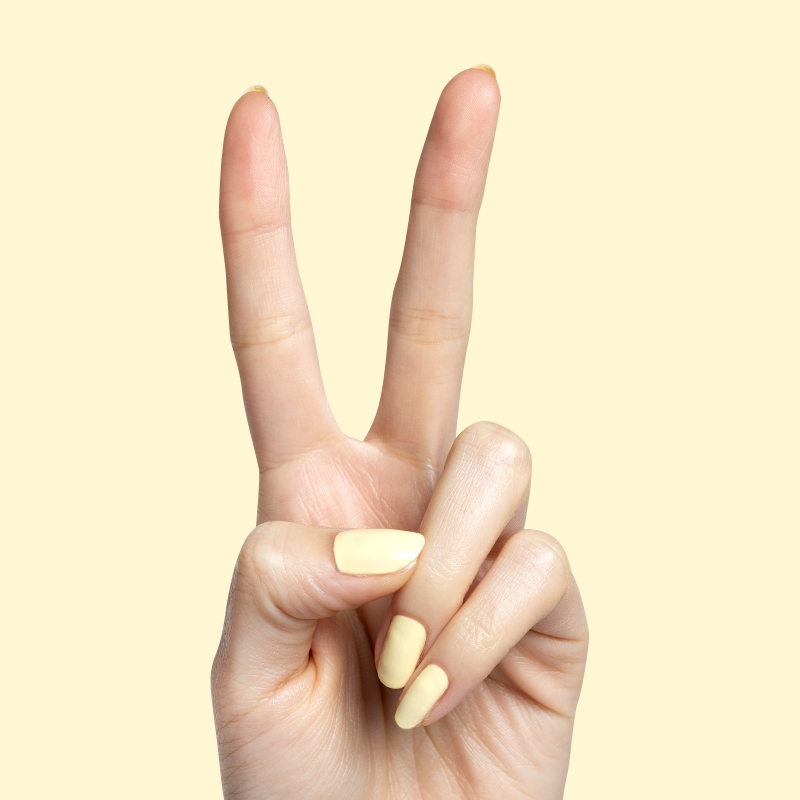Hand with pale yellow nails painted in Sunny polish showing a bright, smooth manicure against a soft yellow background