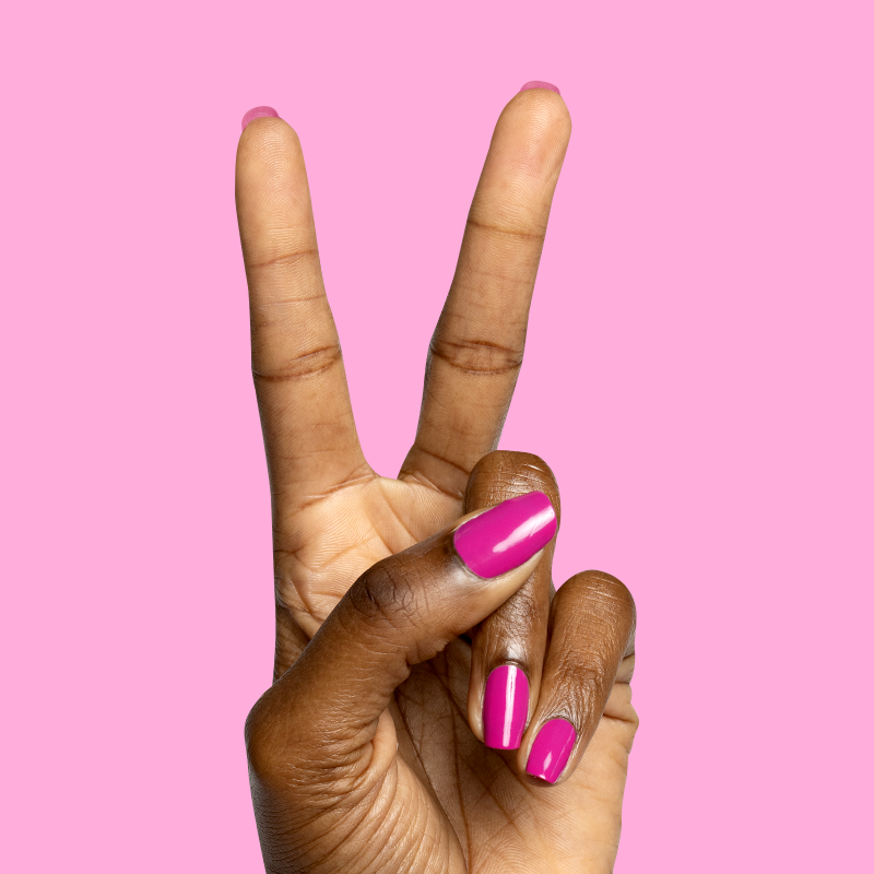 Hand with glossy bright pink nails making a peace sign against pink background with Speed Gloss Top Coat