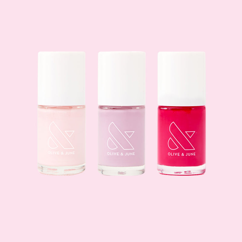 Three nail polish bottles in pink, lavender, and bright red colors from the Spring Minis Set on pale pink background
