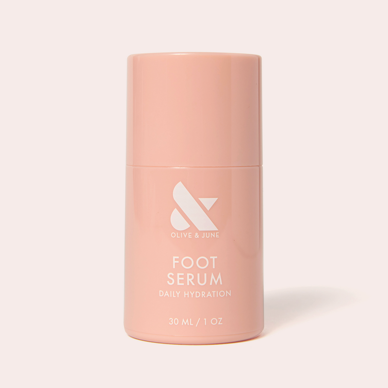 Soft pink bottle of Olive and June Foot Serum for daily hydration shown against light background