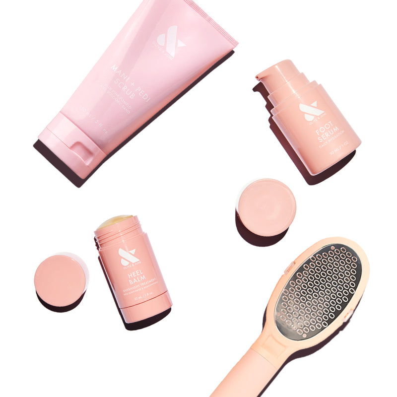 Foot Care Essentials Set with foot serum, heel balm, mani + pedi scrub, and foot file in soft pink packaging