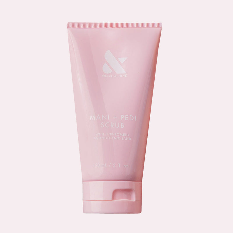 Pink tube of MANI + PEDI SCRUB with gentle exfoliating ingredients for soft, smooth hands and nails by Olive and June