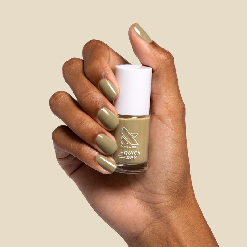 The Quick Dry Set featuring a hand with smooth, quickly dried olive green manicure holding a nail polish bottle