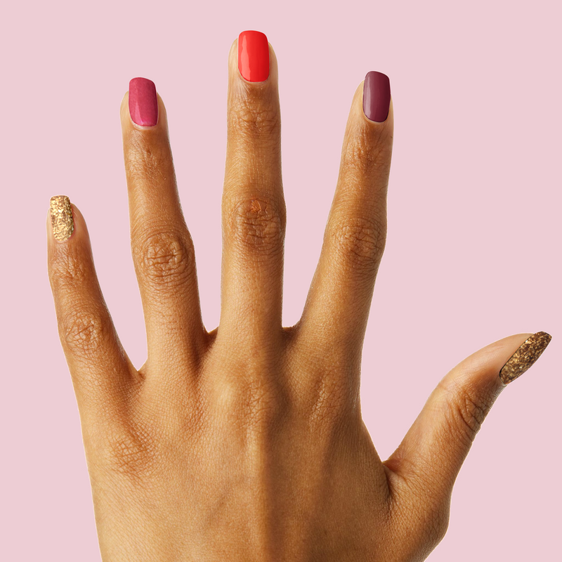 Hand with Cranberry Spritz manicure featuring ruby red, bordeaux, and gold shimmer nail polishes on natural nails