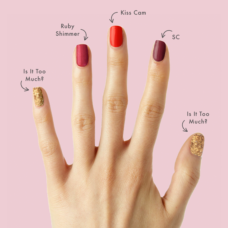 Hand with manicure featuring Cranberry Spritz polish shades ruby shimmer, deep burgundy, bright red, and gold glitter accents
