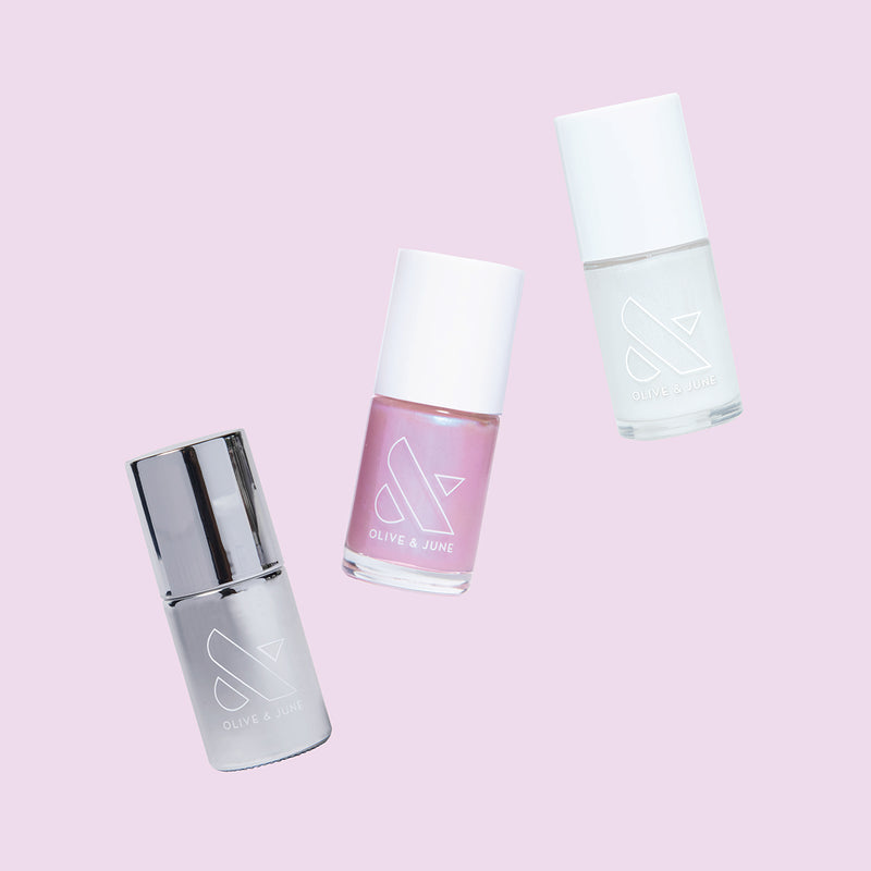 Three nail polish bottles in soft pink and metallic shades from Olive and June’s Pink Opal Set for manicures