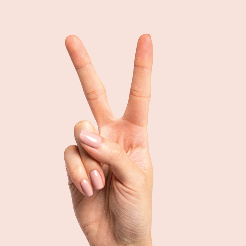 The Quick Dry Set features a fast-drying manicure with long-lasting, smooth nude nail polish on a hand showing a peace sign