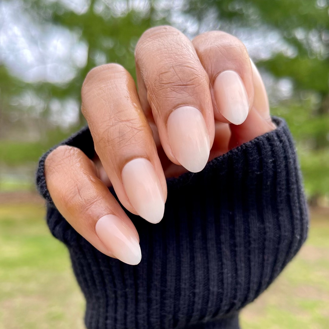 Milky Syrup Gradient - Press-On | Medium | Almond showing hand with medium almond false nails in soft milky white gradient polish outdoors