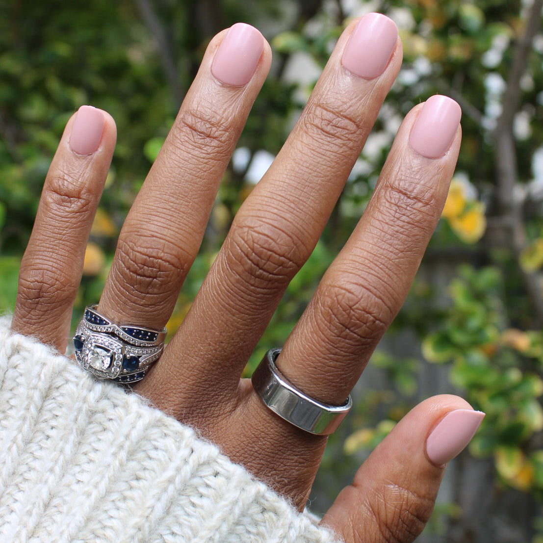 Poodle | Extra Short | Squoval - Tab Press-On nails in soft neutral beigey pink on hand with silver rings outdoors