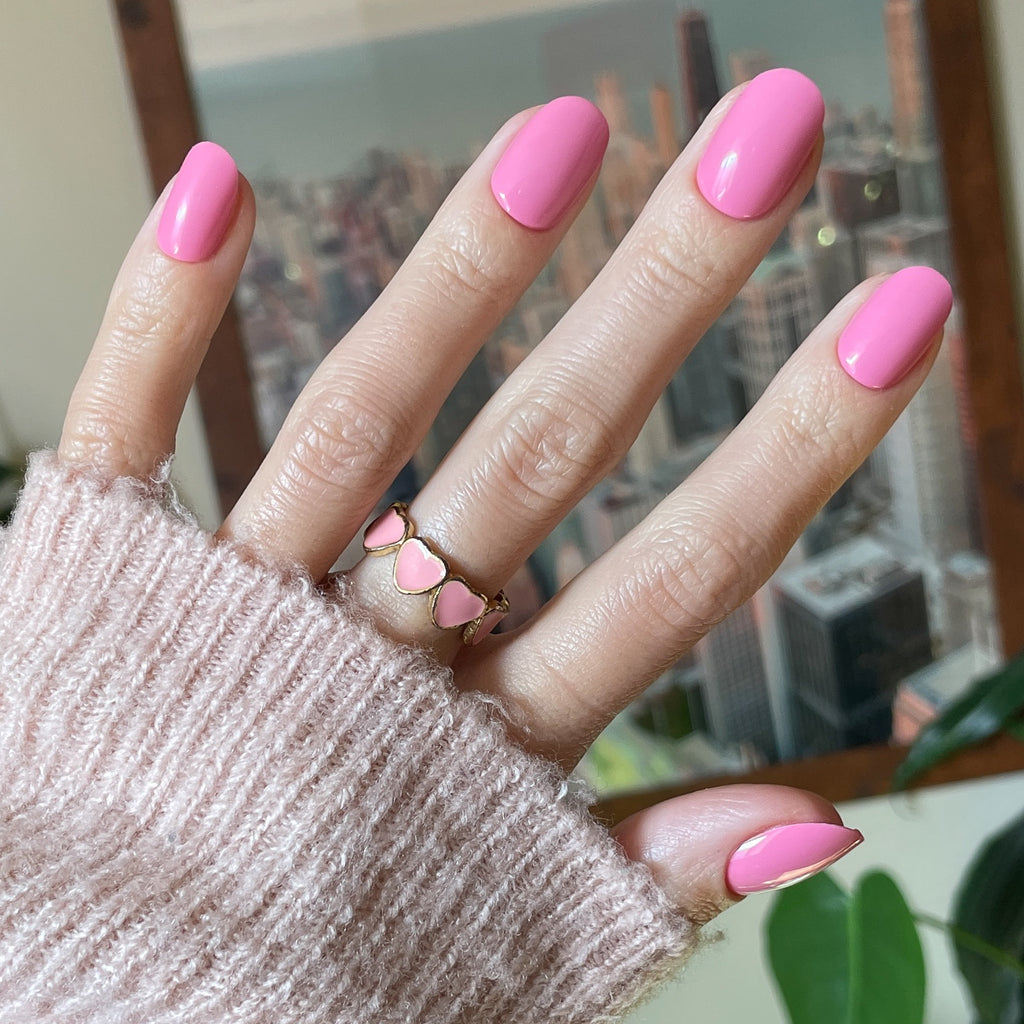 Taffy | Short | Round - Tab Press-On showing bright pink glossy press-on nails on hand with cozy sweater background