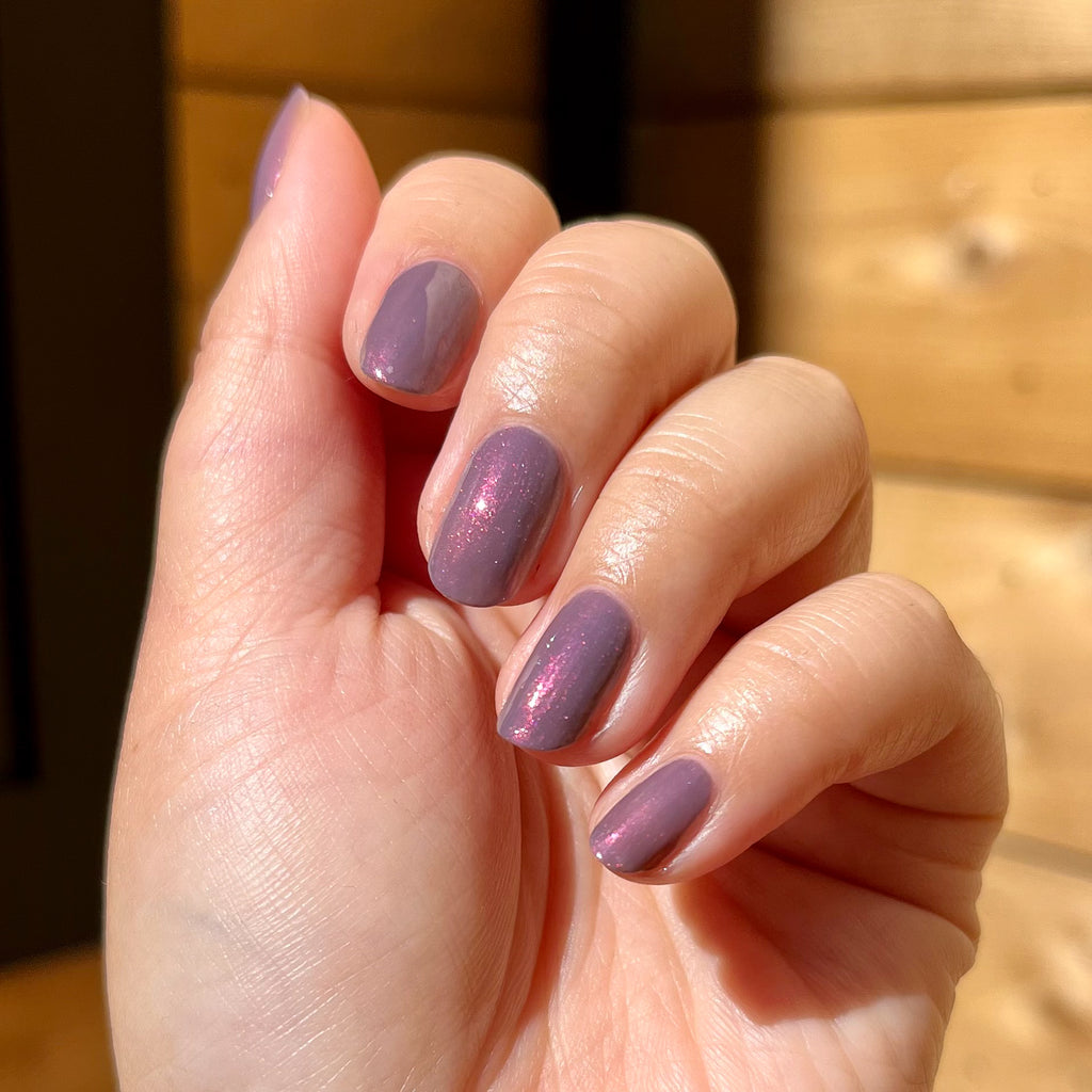 Hand displaying Twilight gel polish in shimmering violet with natural light highlighting the smooth manicure