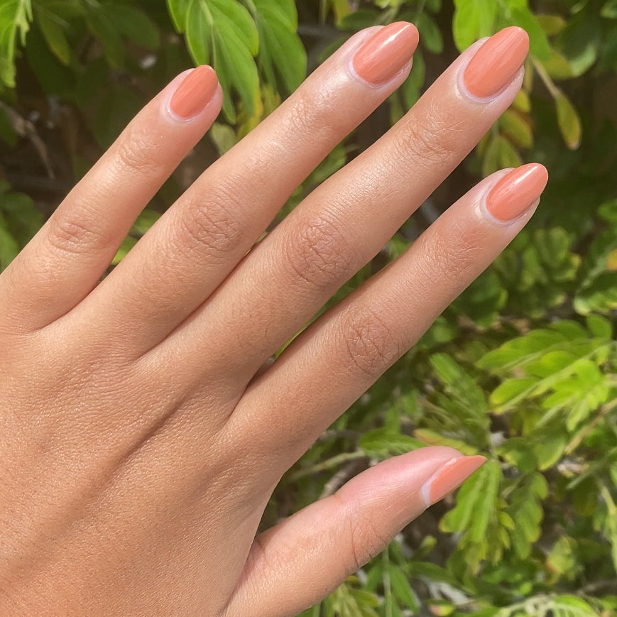 Hand with smooth Canyon gel polish nails in warm desert orange shade for natural and earthy at-home manicure options