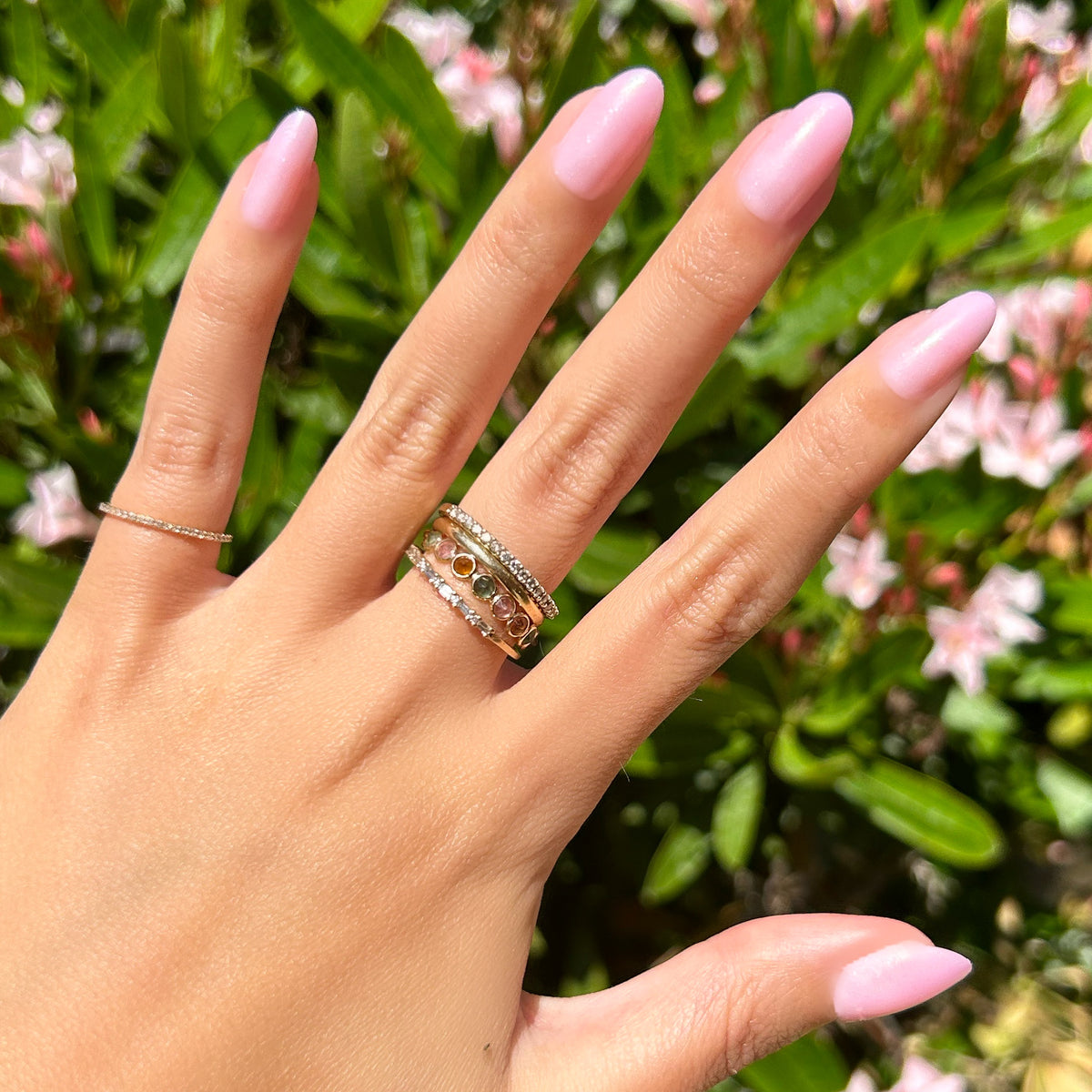 Iridescent Pink - Press-On | Medium | Oval showing hand with medium oval false nails in soft pink iridescent finish outdoors with greenery background