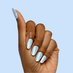 Hand showing nails painted with Aqua Velvet - Gel bright pastel blue magnetic gel polish against light blue background