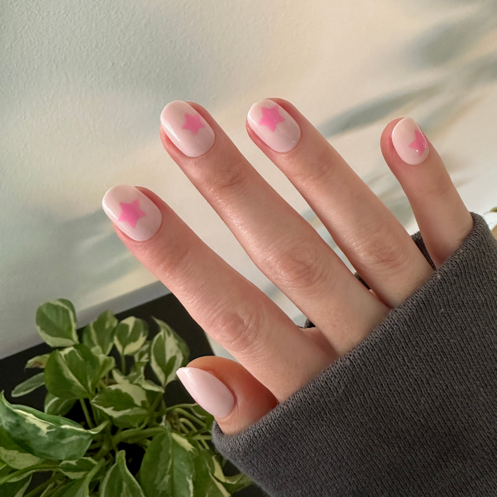 Pink Star Party | Extra Short | Round - Tab Press-On nails with soft pink base and translucent pink star accents on hand