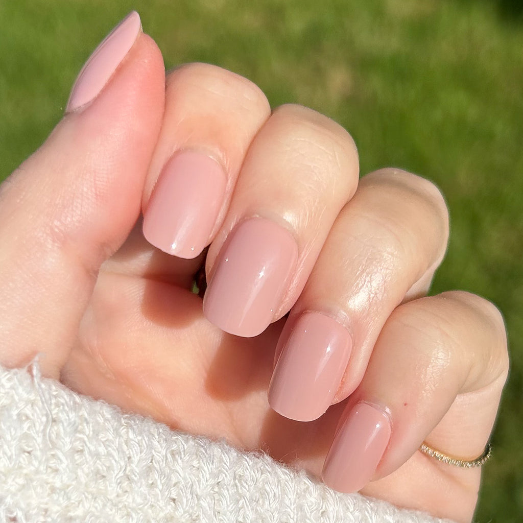 Poodle | Extra Short | Squoval - Tab Press-On nails in soft neutral beige pink polish on hand outdoors with sunlight