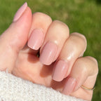 Poodle | Extra Short | Squoval - Tab Press-On nails in soft neutral beige pink polish on hand outdoors with sunlight