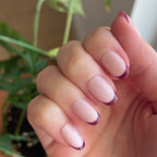 Plum Tonal French - Press-On | Short | Round showing close-up of hand with short round false nails featuring plum French tips indoors near plants