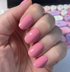 Taffy | Short | Round - Tab Press-On showing smooth glossy sugary pink press-on nails on hand with colorful keyboard background