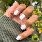 Swan | Extra Short | Squoval - Tab Press-On showing hand with crisp white nails outdoors against natural green background