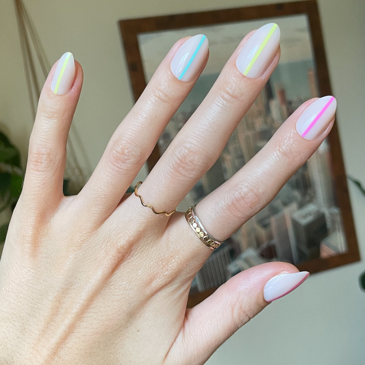 Neon Lines - Press-On | Medium | Almond showing hand with neutral manicure featuring bright vertical lines on medium almond press-on nails