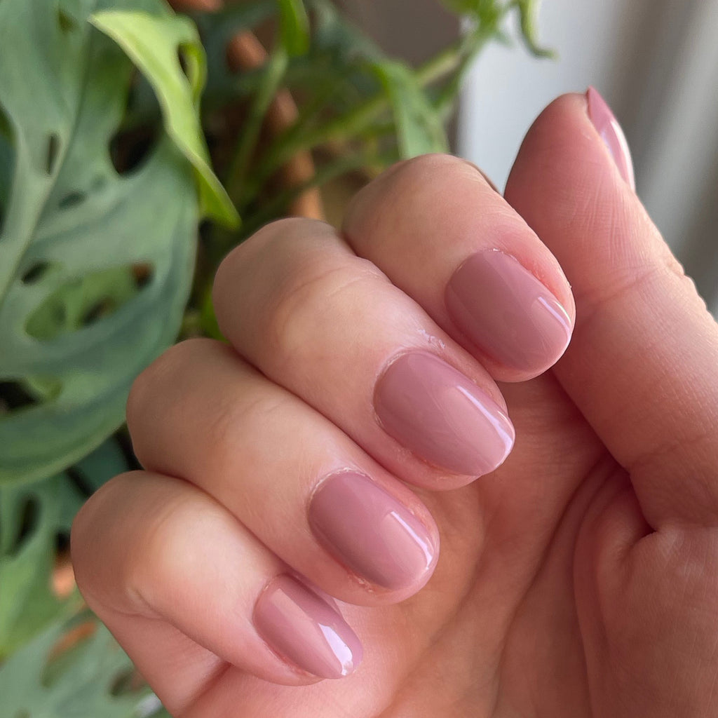 World Lit - Press-On | Extra Short | Round showing close-up of hand with glossy mauve extra short round press-on manicure