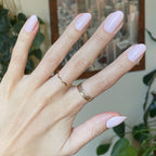 GH - Press-On | Medium | Oval showing hand with medium oval glossy baby pink press-on manicure indoors near plants and framed art