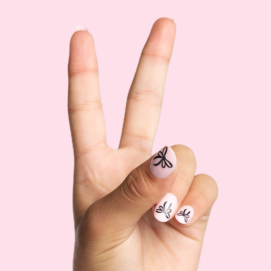 Biggest Bow On Top - Pressies | Short Medium | Round showing light pink press-on nails with black bow design on pale pink background
