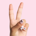 Biggest Bow On Top - Pressies | Short Medium | Round showing light pink press-on nails with black bow design on pale pink background
