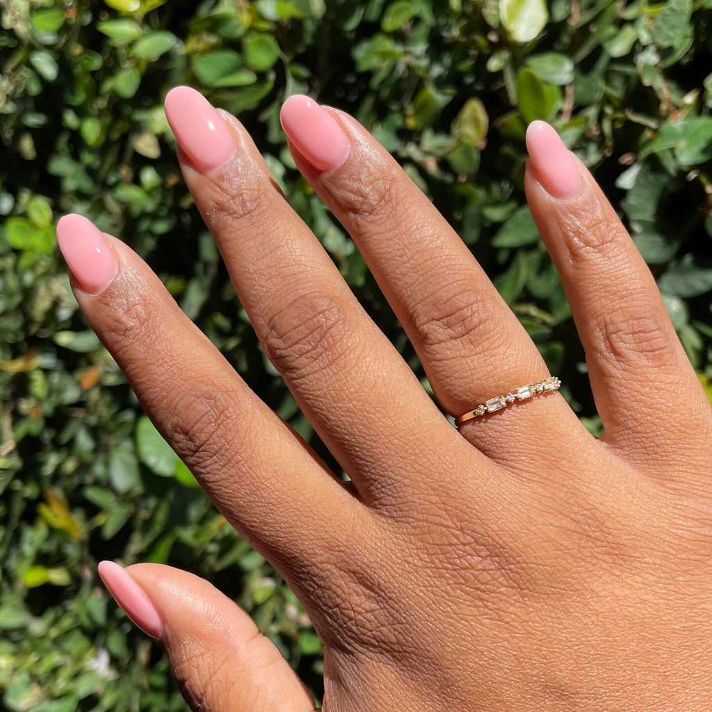 Bubble Gloss - Builder Gel on almond-shaped nails with a glossy bright pink manicure against green leafy background