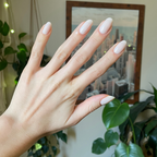 Hand with long natural nails featuring Buttercream sheer milky white polish for a smooth, elegant manicure look