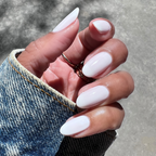 Hand with medium-length nails coated in Buttercream for a sheer, frosted manicure look outdoors