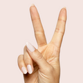 Hand showing long nails painted with CDJ - Gel creamy neutral gel polish on light beige background thumbnail