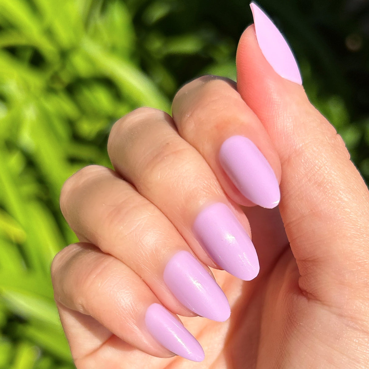 You're Invited - Press-On | Medium | Almond showing hand with playful lilac medium almond press-on manicure outdoors in natural light