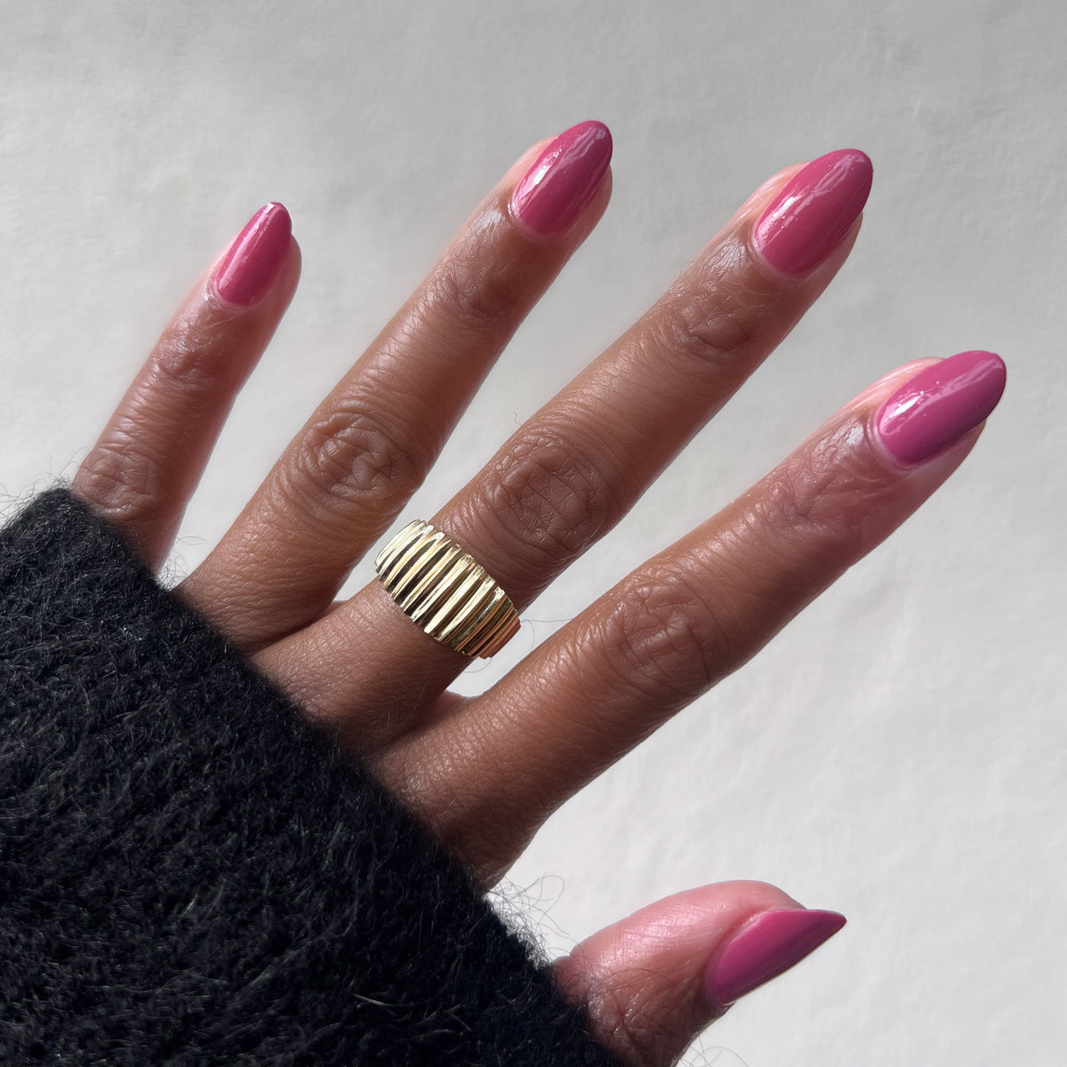 Hand with Primrose gel polish in warm rosey pink showing a smooth manicure and gold ring on medium skin tone