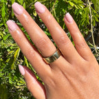 Poodle | Extra Short | Squoval - Tab Press-On nails in soft neutral beigey pink polish on hand outdoors with gold band ring