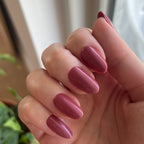 LD - Press-On | Medium | Oval showing hand with medium oval rosy mauve press-on manicure indoors near window light and plants