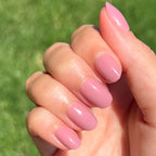 World Lit - Press-On | Extra Short | Round showing hand with mauve extra short round press-on manicure in natural light outdoors