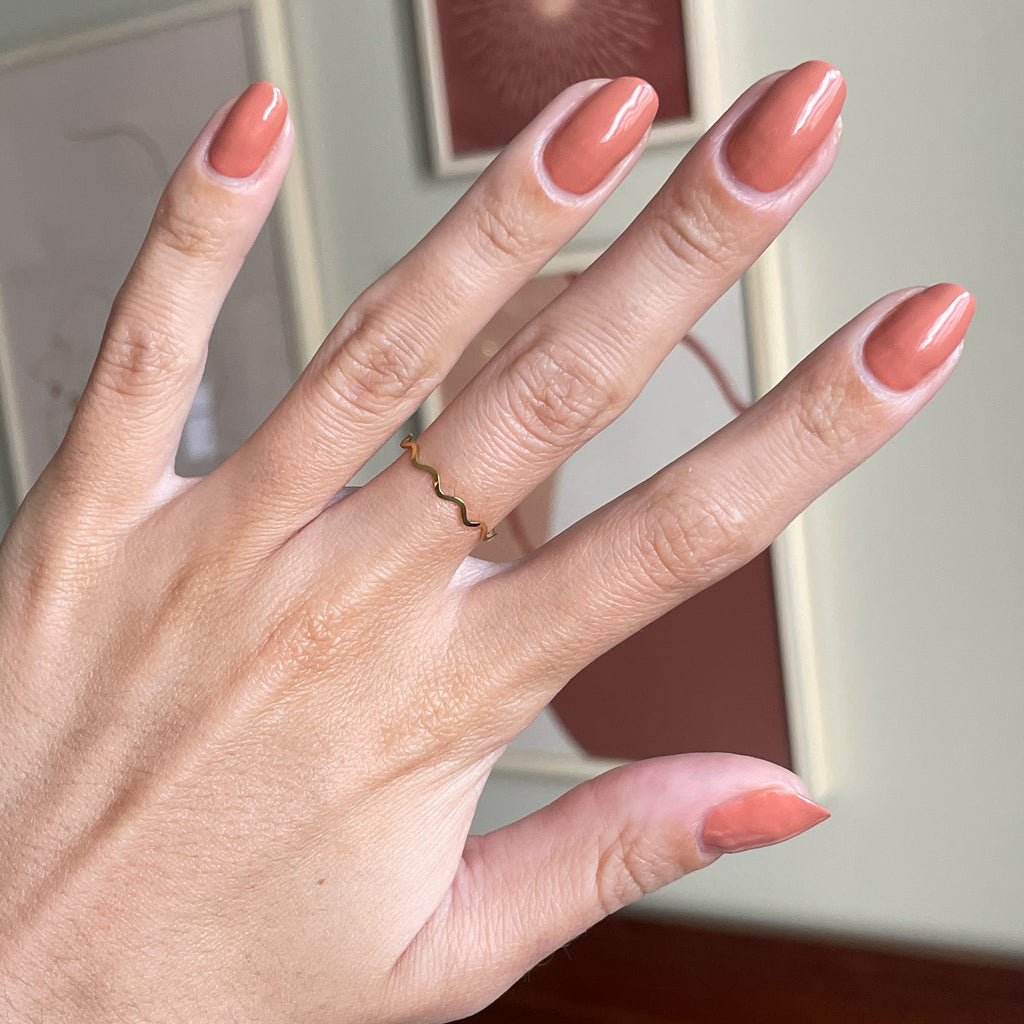 Hand with Canyon gel polish in warm desert orange shade for smooth, natural-looking at-home manicure and long-lasting mani options