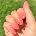 Pink Jelly - Press-On | Short | Round showing hand outdoors with sheer pink jelly press-on manicure in natural light