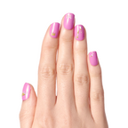 Hand with pink polish adorned with gold Celebration nail stickers including crown, bow, champagne glasses, and party banner for mani designs